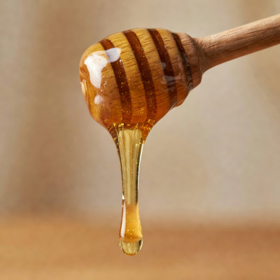 Macro shot of honey being drizzled from a wooden honey dipper